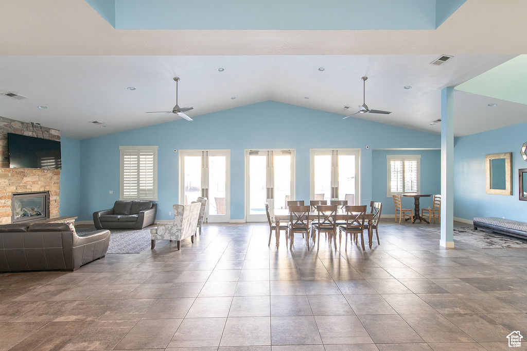 Dining space featuring a ceiling fan, healthy amount of natural light, vaulted ceiling, and a fireplace