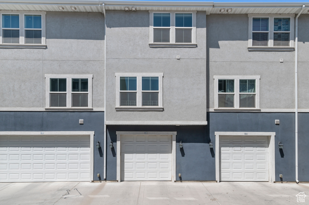 View of front of home with stucco siding, a garage, and driveway