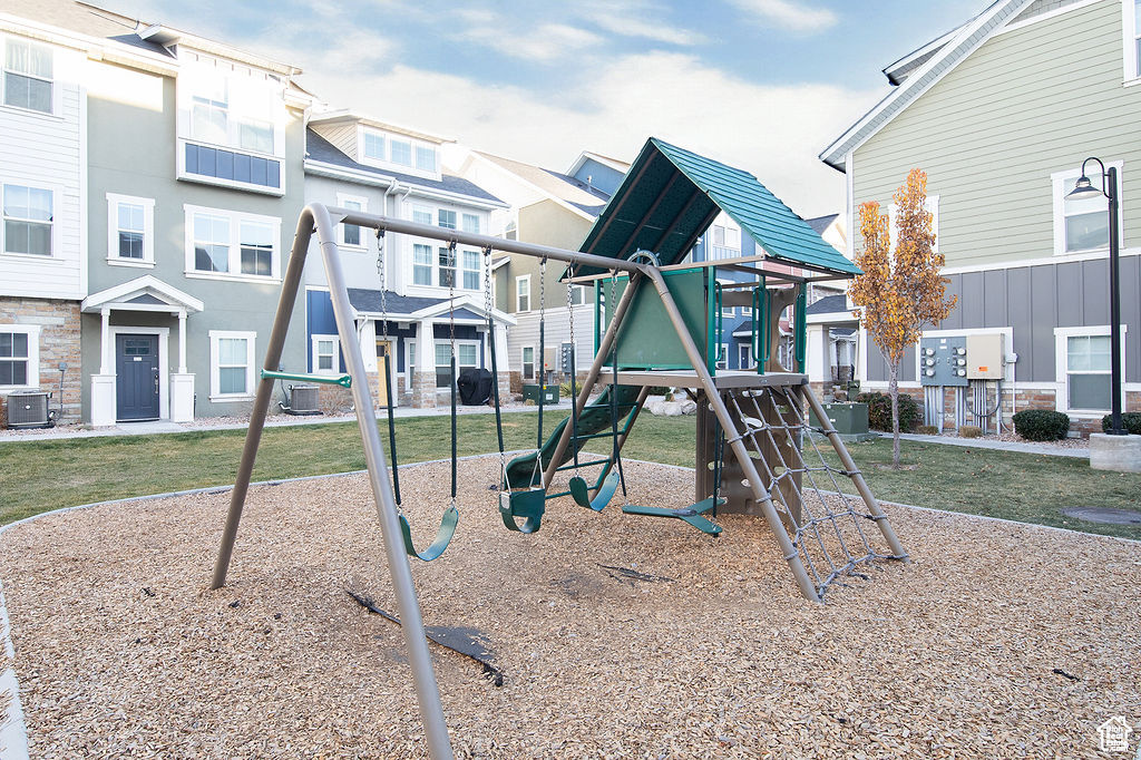 Community playground with a residential view, cooling unit, and a lawn