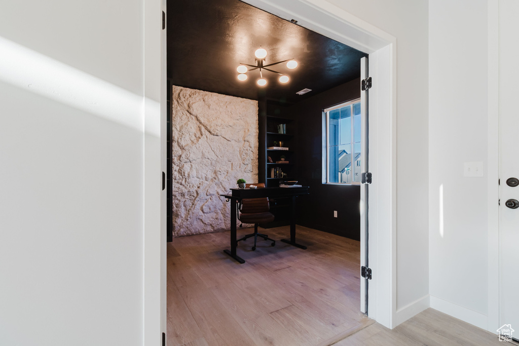 Home office with light wood finished floors and a chandelier