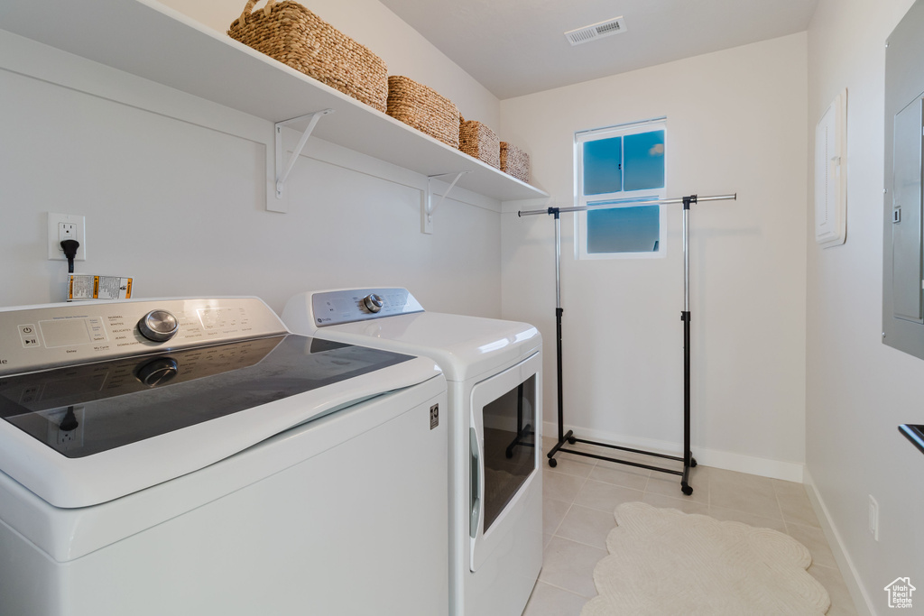Laundry room with washing machine and clothes dryer, light tile patterned flooring, and baseboards