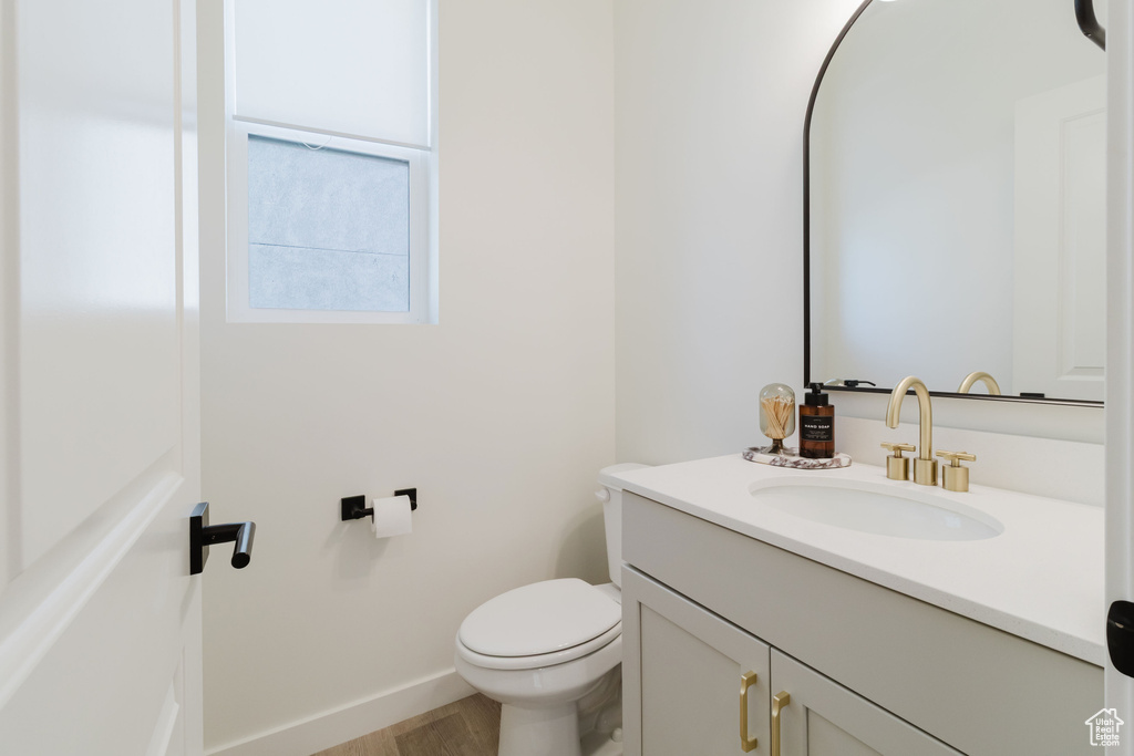 Bathroom with vanity, toilet, baseboards, and wood finished floors