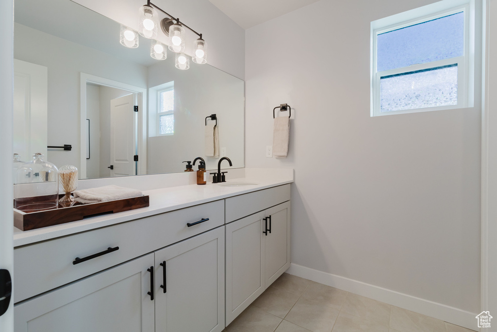 Bathroom with baseboards, double vanity, and tile patterned flooring