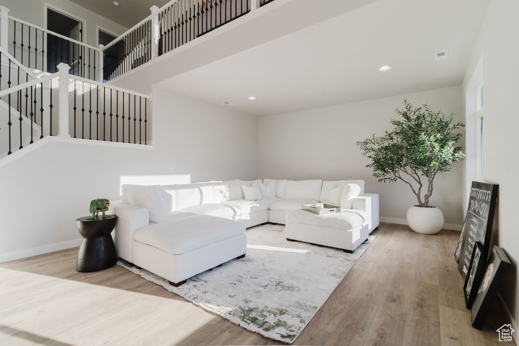 Living room featuring wood finished floors, baseboards, recessed lighting, and a towering ceiling