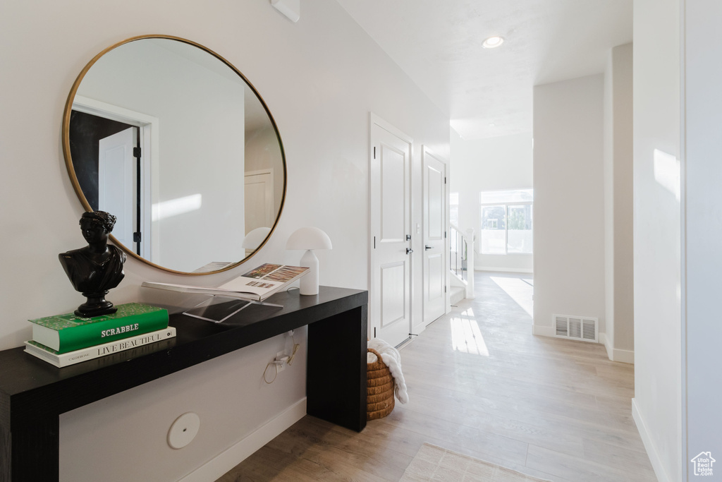 Hallway featuring light wood finished floors, baseboards, and recessed lighting