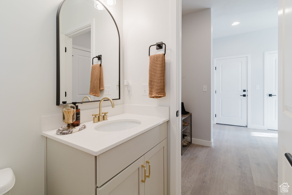 Bathroom with vanity, wood finished floors, baseboards, and recessed lighting