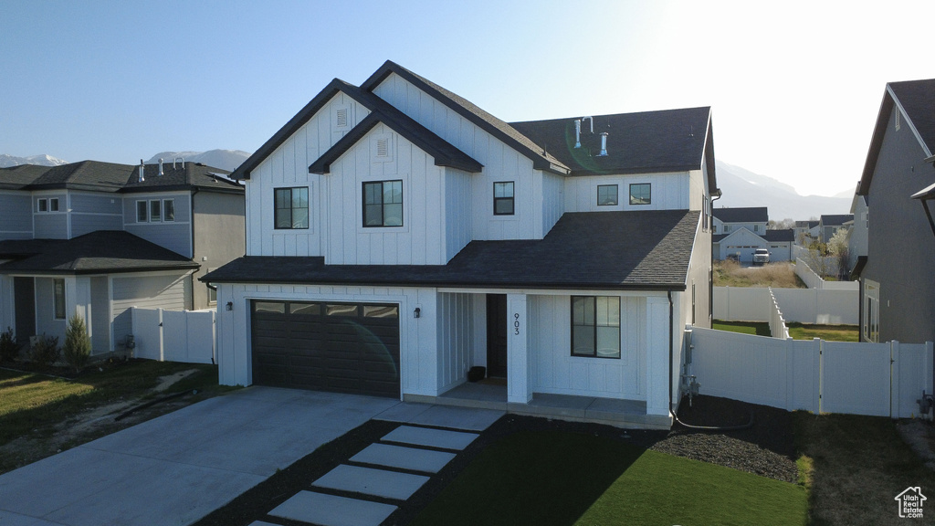 Modern inspired farmhouse with board and batten siding, concrete driveway, a garage, a mountain view, and covered porch