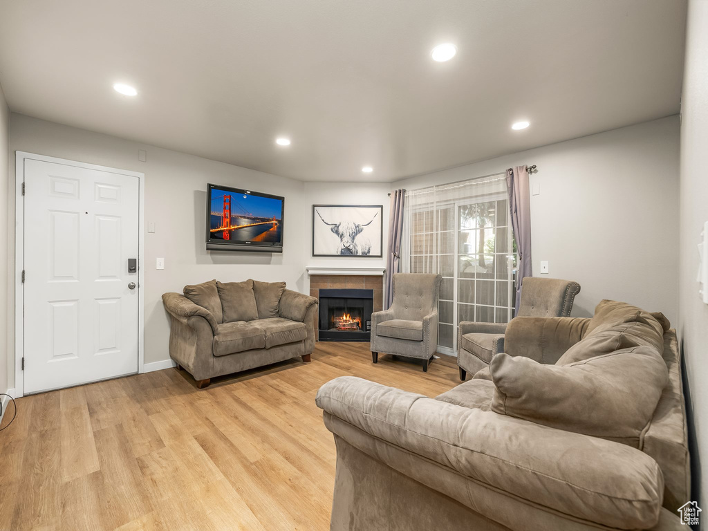 Living room with a fireplace, light wood finished floors, recessed lighting, and baseboards