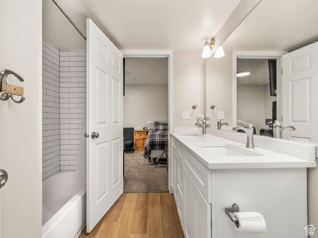 Full bathroom with double vanity, wood finished floors, ensuite bathroom, and tub / shower combination
