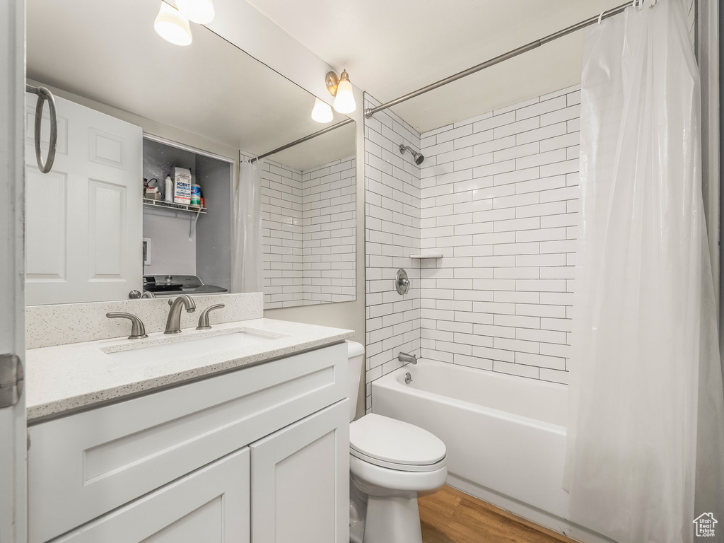 Full bath featuring toilet, shower / tub combo, vanity, and wood finished floors