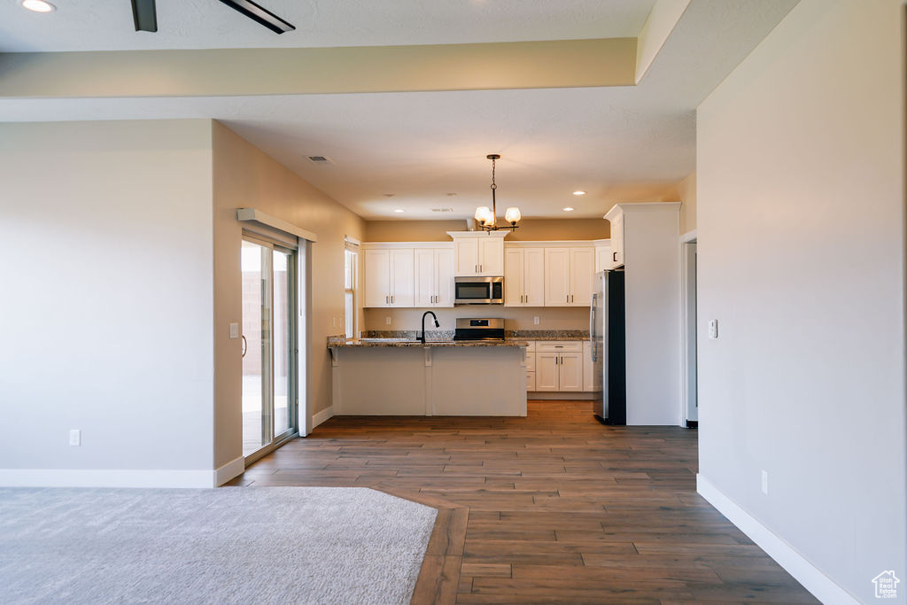 Kitchen with stainless steel appliances, white cabinets, a peninsula, recessed lighting, and baseboards