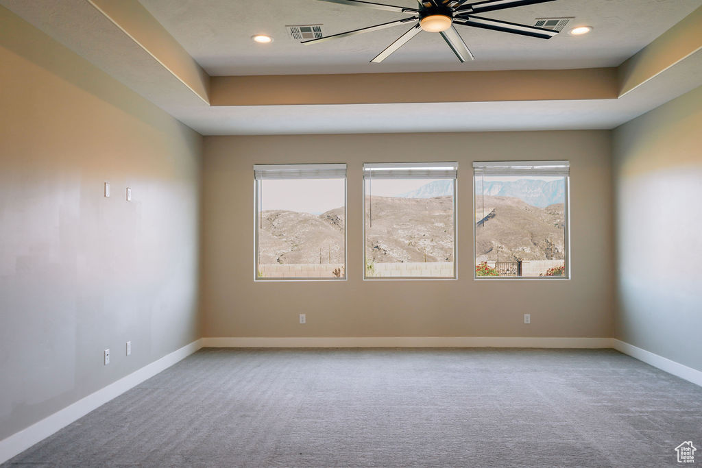 Carpeted spare room featuring baseboards, recessed lighting, ceiling fan, and a raised ceiling