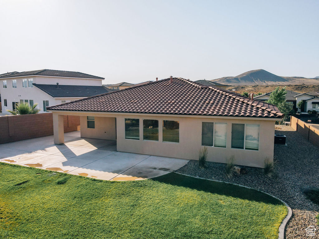 Rear view of house with stucco siding, a tile roof, a patio, and a mountain view