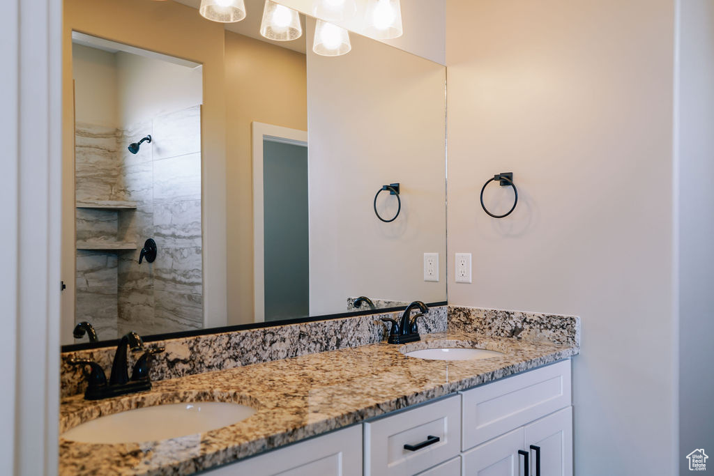 Bathroom featuring double vanity and tiled shower