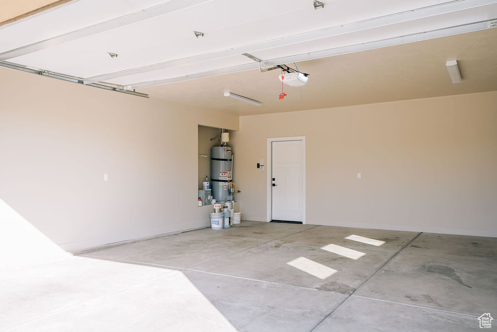 Garage featuring water heater, a garage door opener, and baseboards