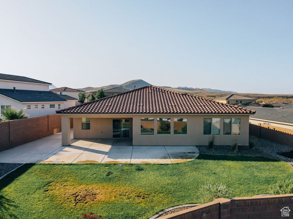 Rear view of property featuring stucco siding, a tiled roof, and a patio area