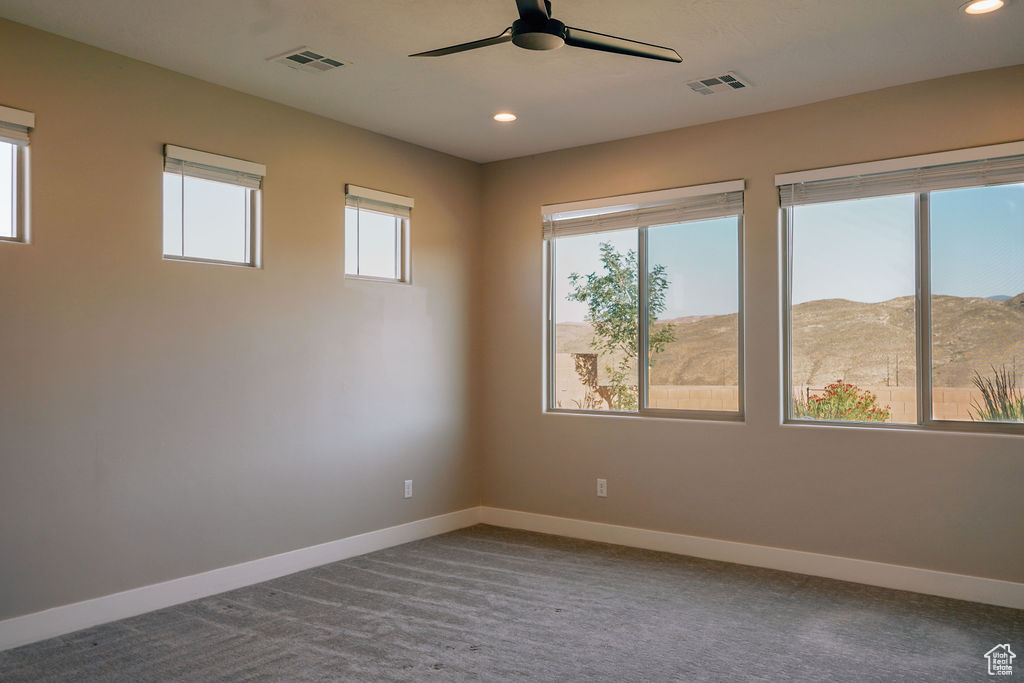 Carpeted spare room featuring baseboards, plenty of natural light, ceiling fan, recessed lighting, and a mountain view