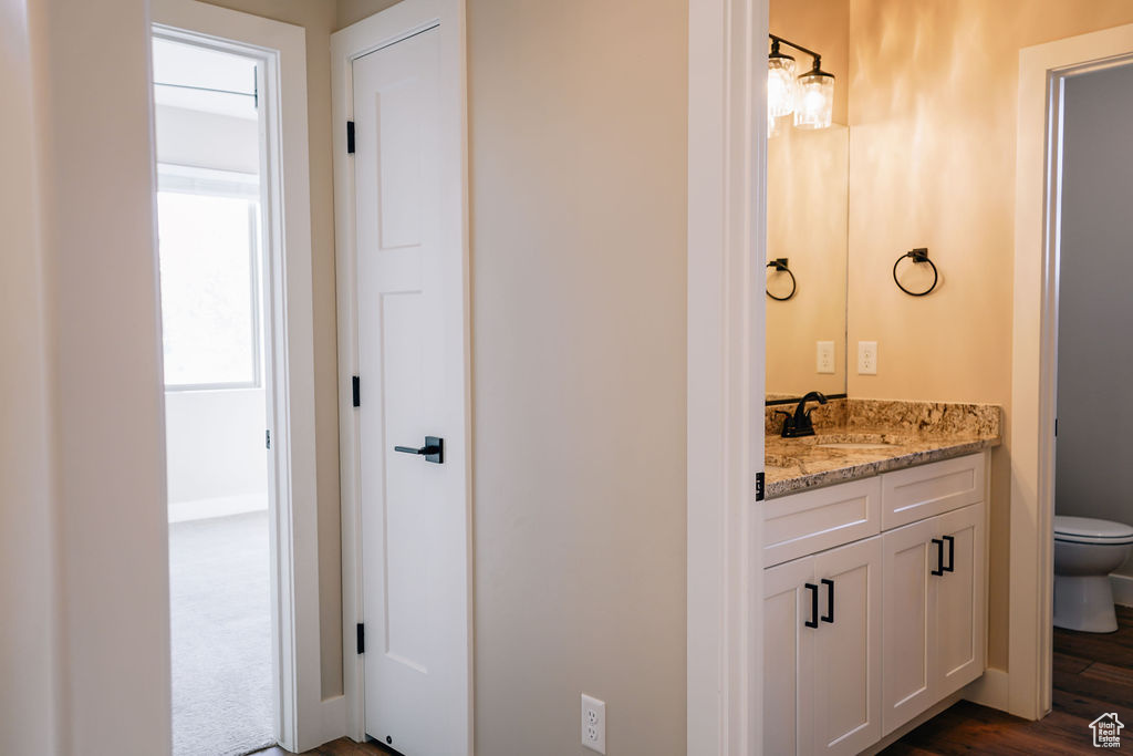 Bathroom featuring toilet, vanity, baseboards, and wood finished floors