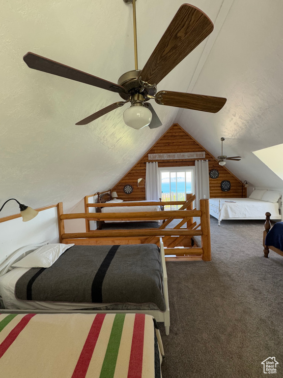 Bedroom featuring wooden walls, vaulted ceiling, and carpet