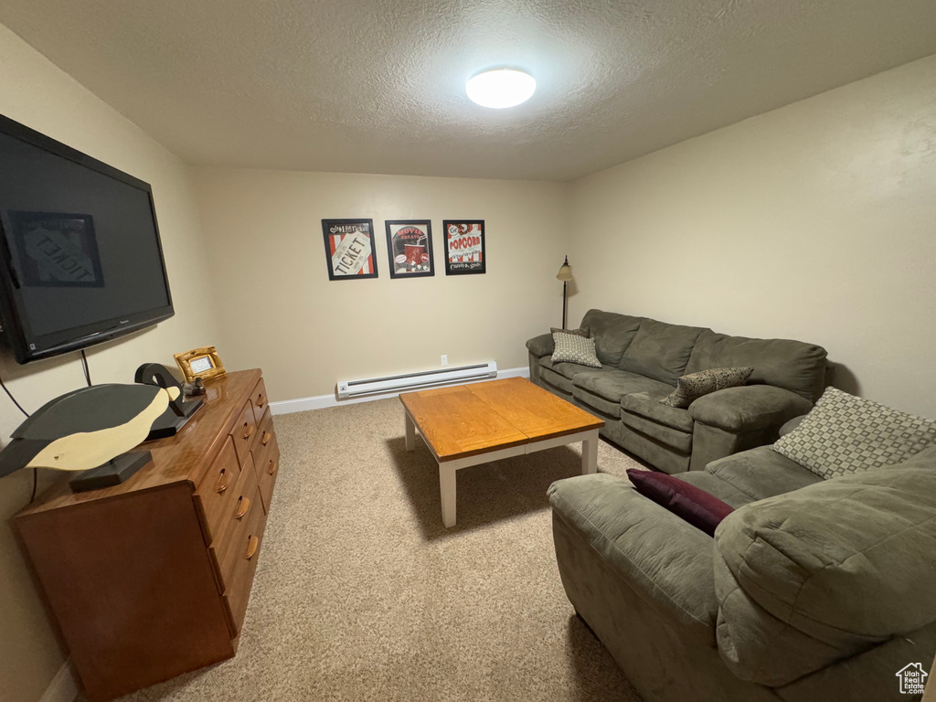 Living area featuring a baseboard radiator, a textured ceiling, and carpet flooring