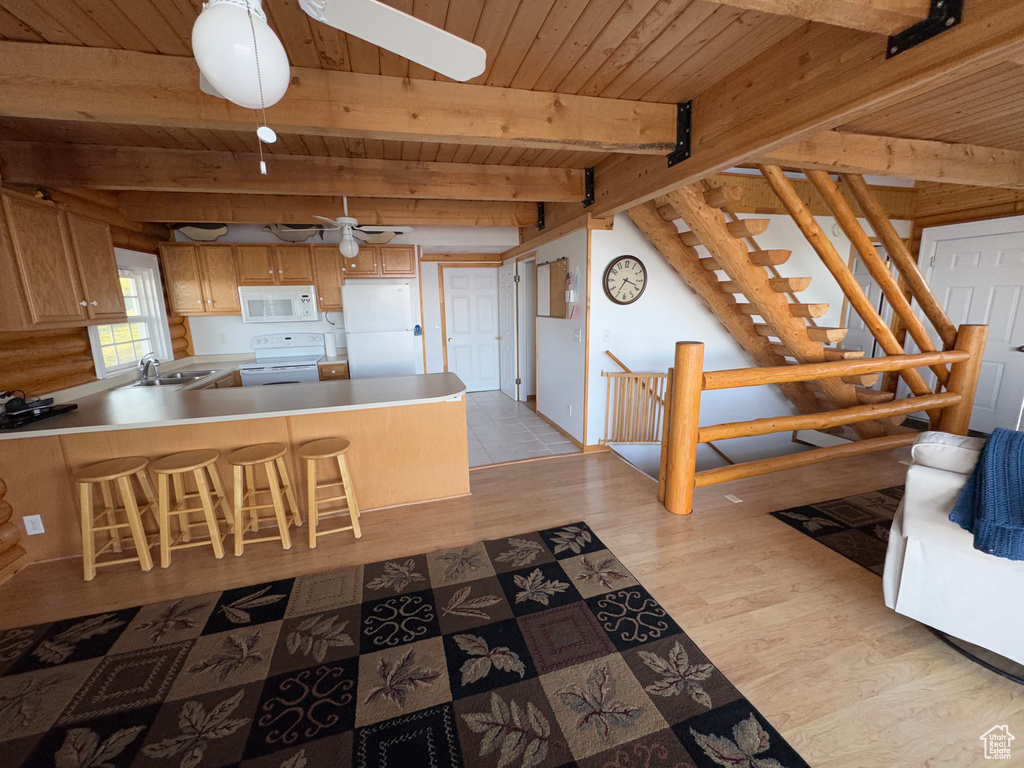 Kitchen with white appliances, a sink, wooden ceiling with exposed beams, a ceiling fan, and light wood finished floors