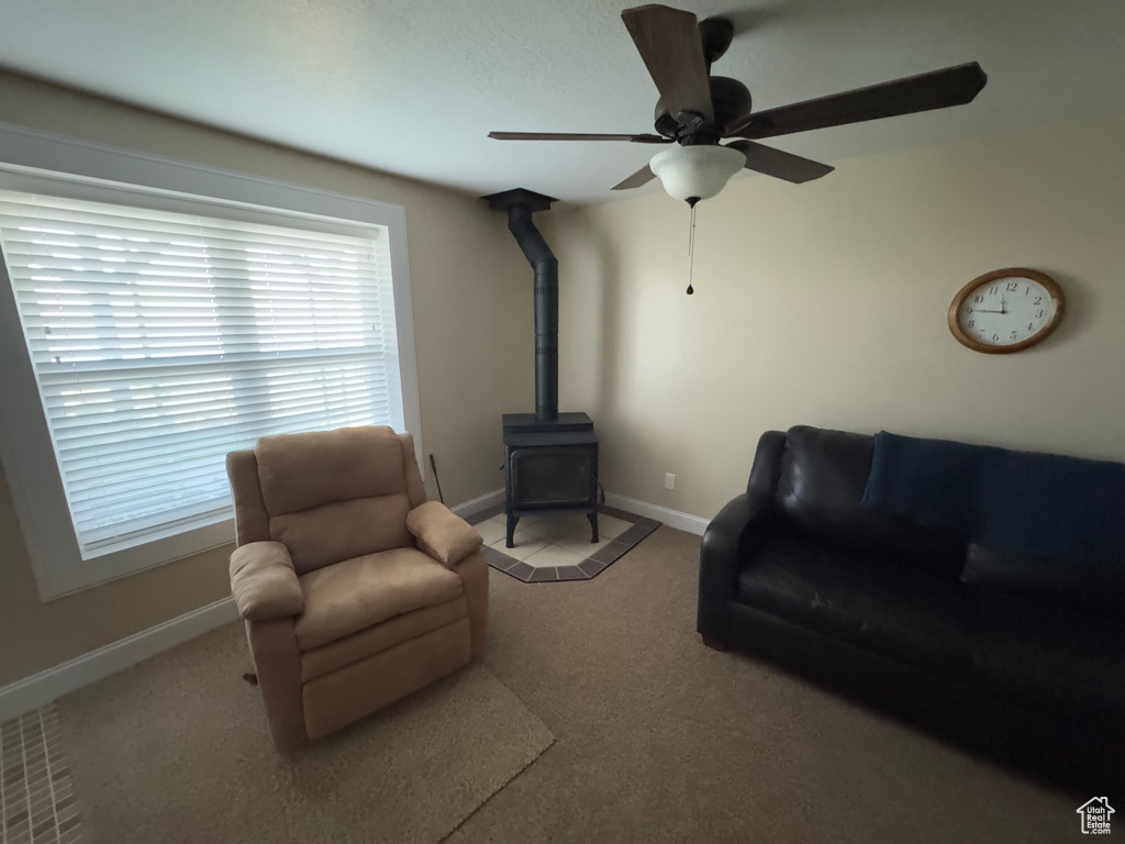 Carpeted living area featuring a wood stove and ceiling fan