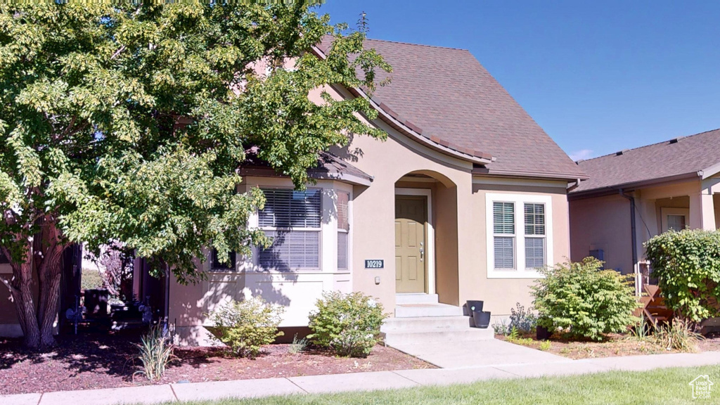 View of front of home featuring stucco siding and roof with shingles