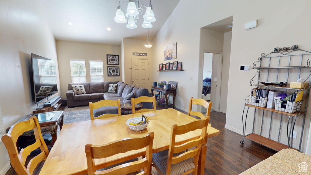 Dining area with wood finished floors, a chandelier, lofted ceiling, and baseboards