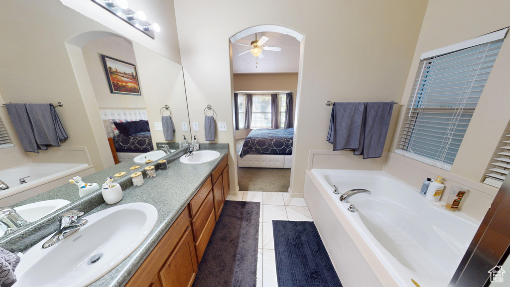 Ensuite bathroom with a ceiling fan, a garden tub, double vanity, and tile patterned flooring