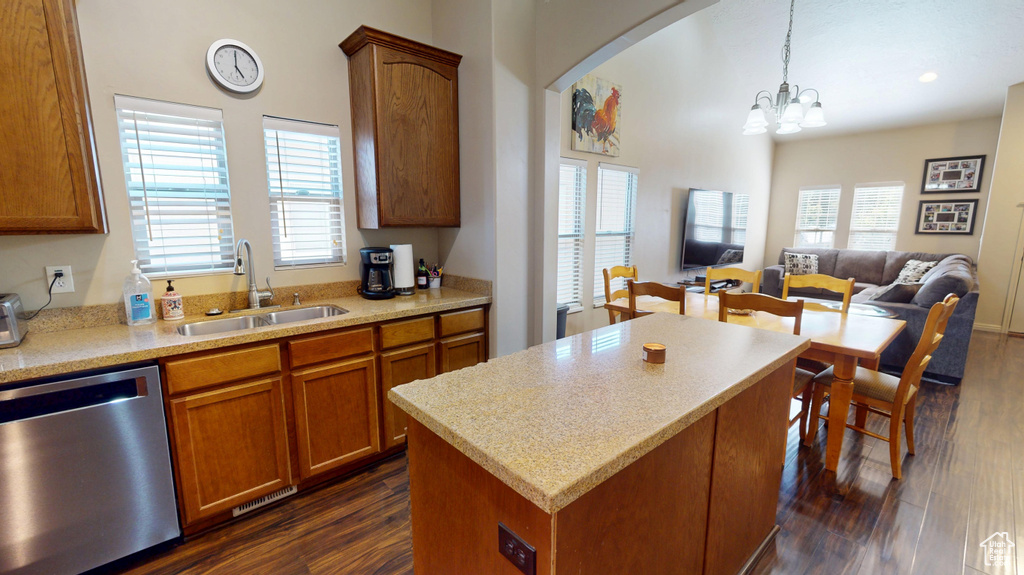 Kitchen featuring stainless steel dishwasher, a sink, open floor plan, dark wood finished floors, and brown cabinets