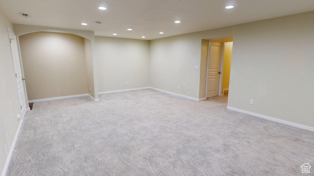 Empty room with recessed lighting, arched walkways, light colored carpet, and baseboards