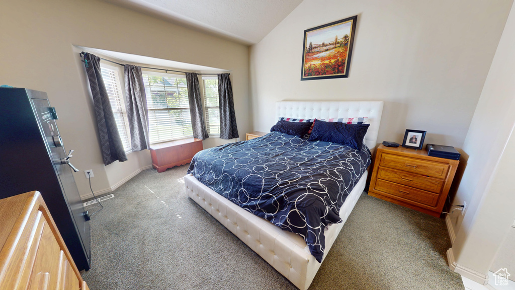 Carpeted bedroom featuring vaulted ceiling and baseboards