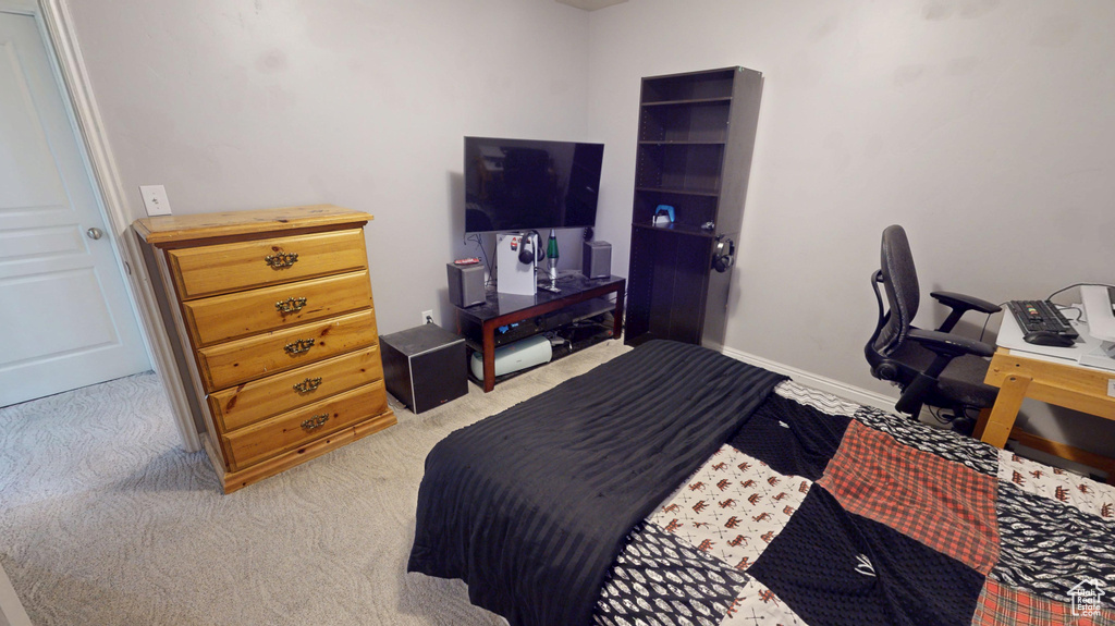 Bedroom with light colored carpet and an office area