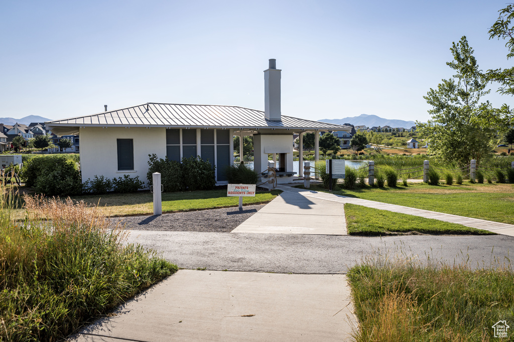 View of front of home with a chimney, a standing seam roof, a mountain view, stucco siding, and a front lawn