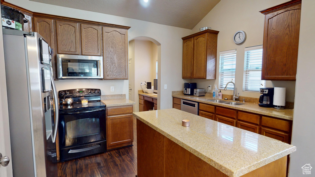 Kitchen with appliances with stainless steel finishes, a sink, dark wood-type flooring, light countertops, and vaulted ceiling