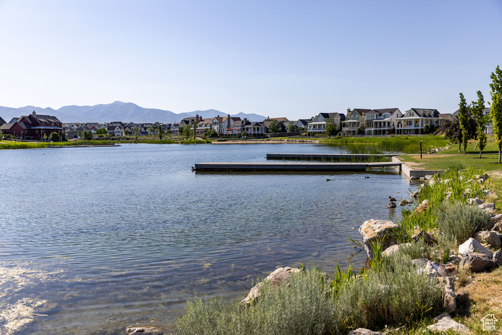 Water view featuring nearby suburban area, a floating dock, and a mountainous background