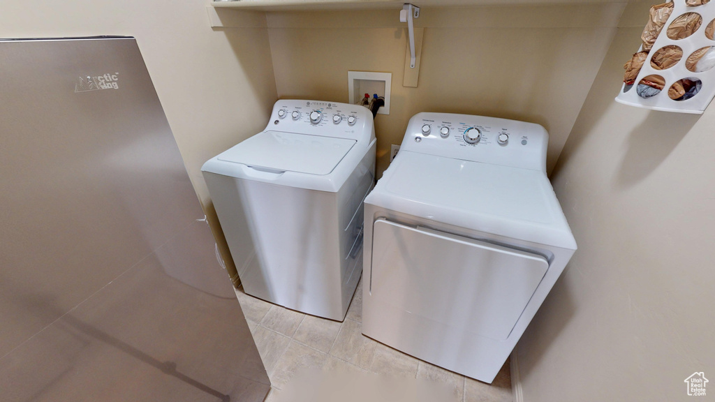 Laundry area featuring separate washer and dryer and light tile patterned floors