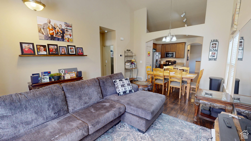 Living area featuring arched walkways, wood finished floors, a towering ceiling, and a chandelier
