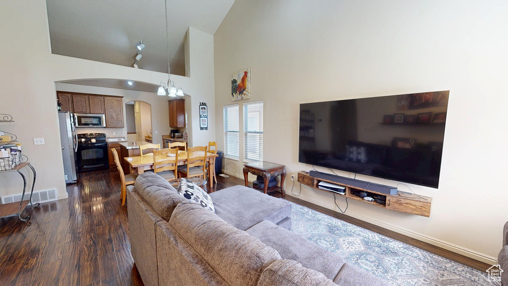 Living area featuring arched walkways, baseboards, dark wood finished floors, and high vaulted ceiling