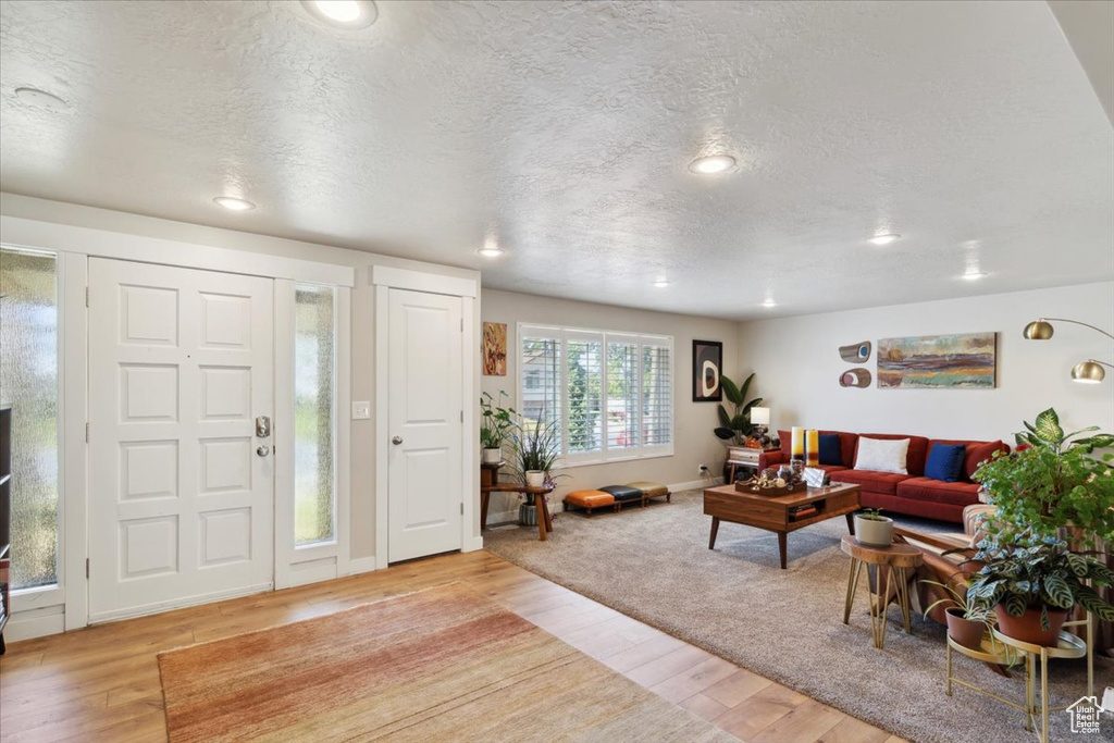 Entrance foyer featuring a textured ceiling, light wood-type flooring, recessed lighting, and baseboards