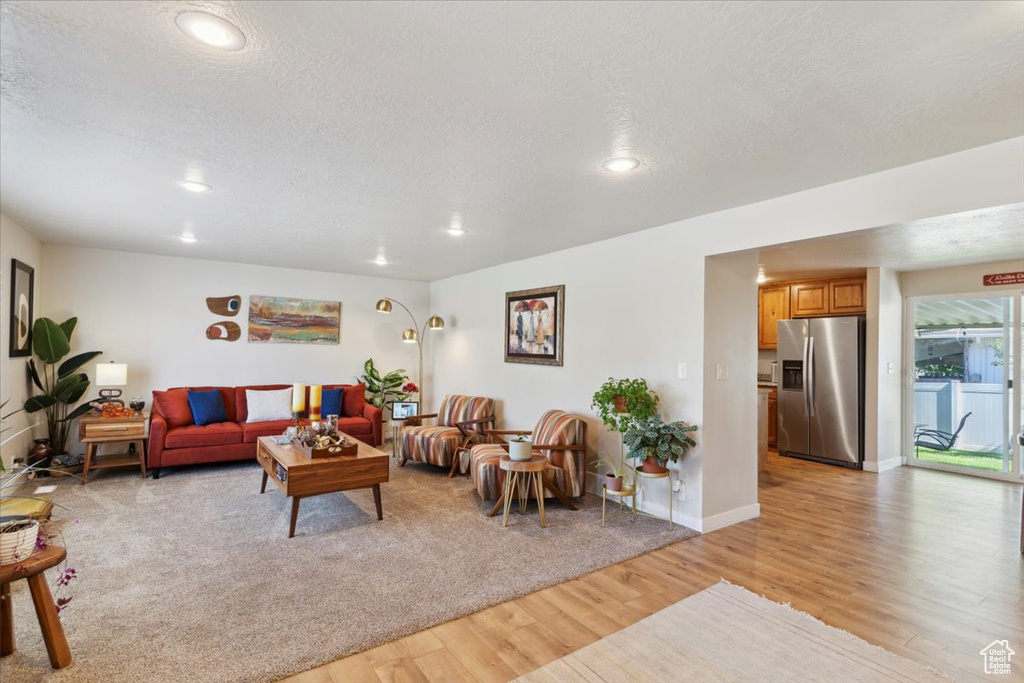 Living area featuring light wood-style flooring, a textured ceiling, recessed lighting, and baseboards