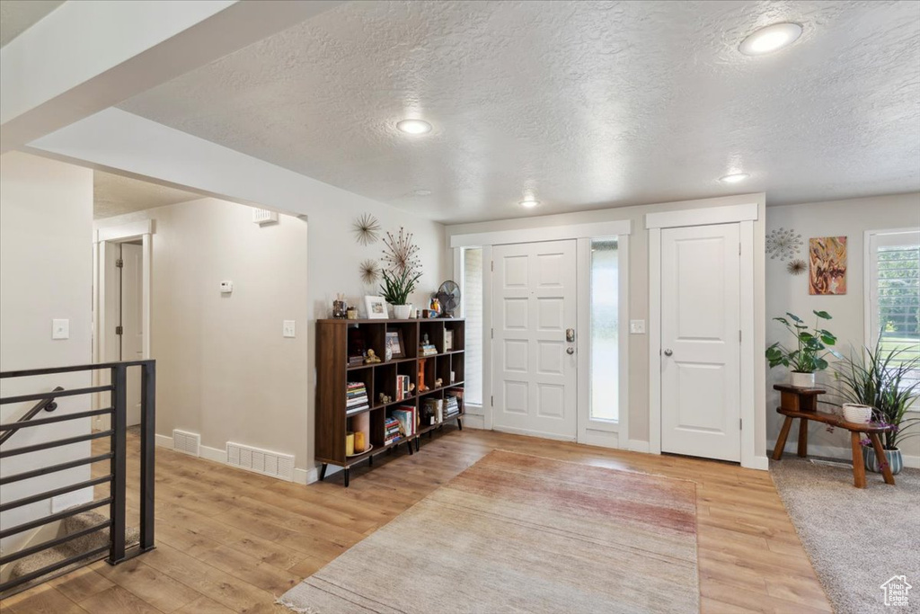 Foyer entrance featuring a textured ceiling, light wood finished floors, baseboards, and recessed lighting