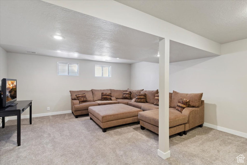 Living area with a textured ceiling, light carpet, baseboards, and recessed lighting