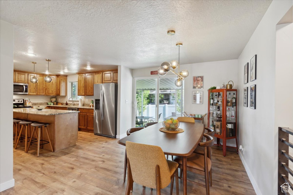 Dining area featuring light wood-style flooring, plenty of natural light, baseboards, and a textured ceiling