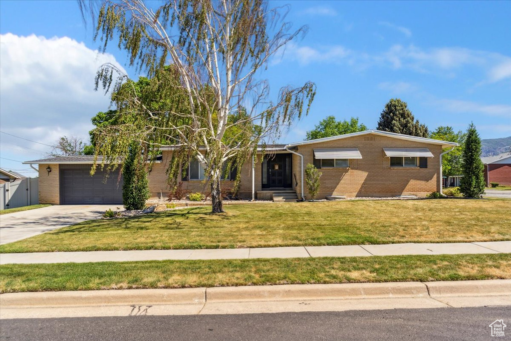 Ranch-style house featuring brick siding, concrete driveway, a front yard, and a garage