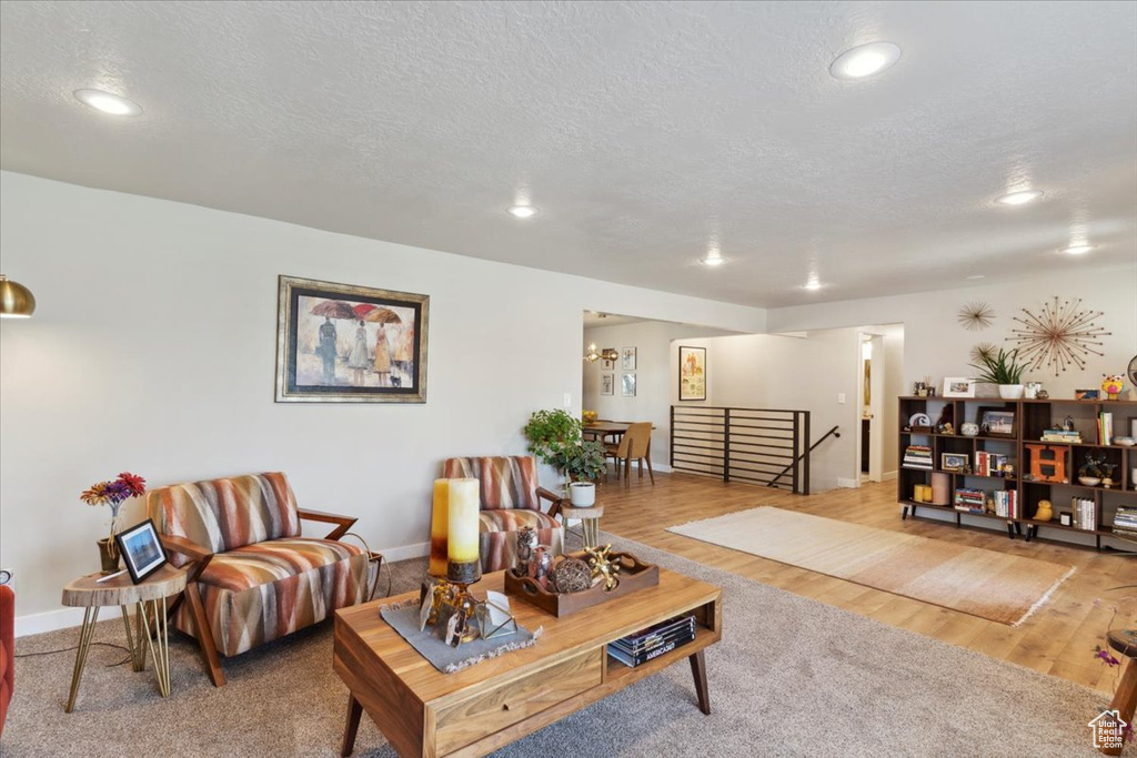 Living area with a textured ceiling, recessed lighting, baseboards, and wood finished floors