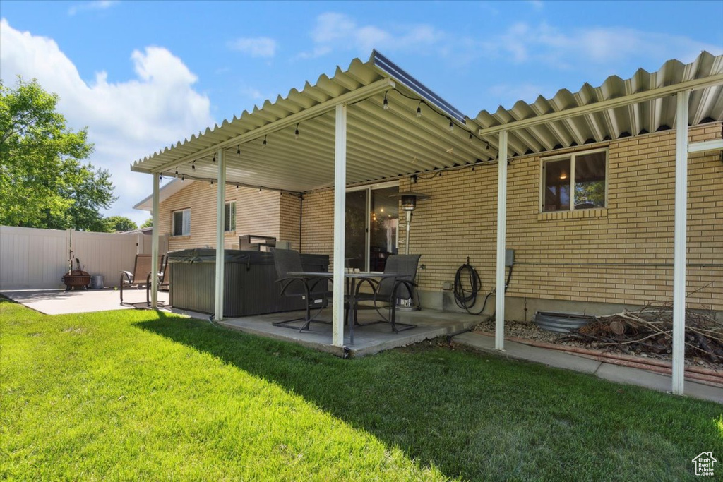 Rear view of house with a hot tub, a patio area, and brick siding