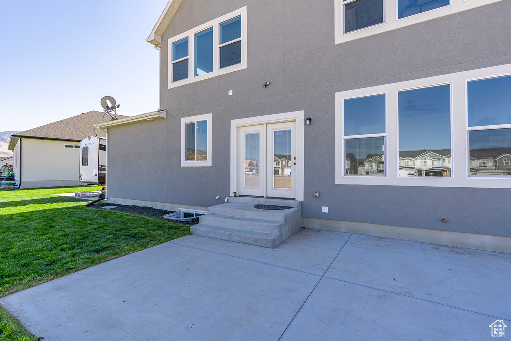 Back of house featuring a lawn, a patio area, and stucco siding