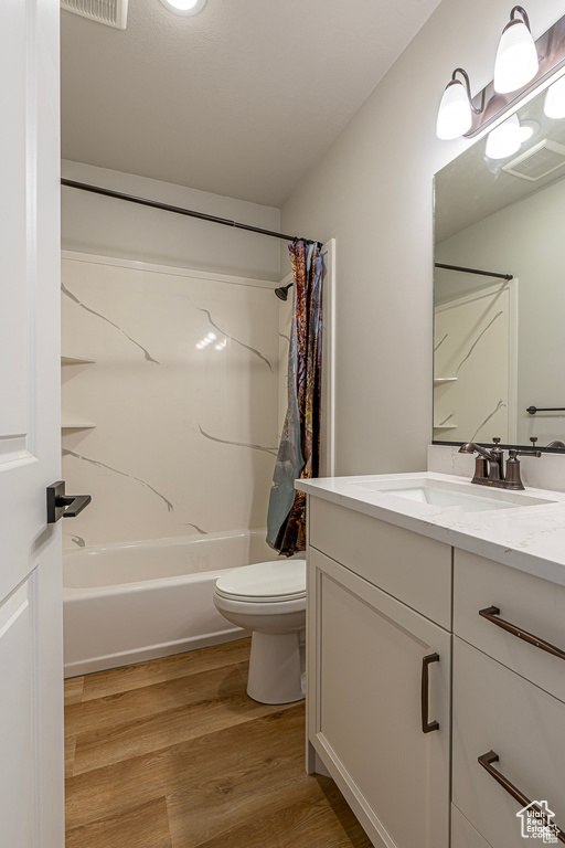 Full bath with vanity, toilet, shower / bath combination with curtain, and wood finished floors