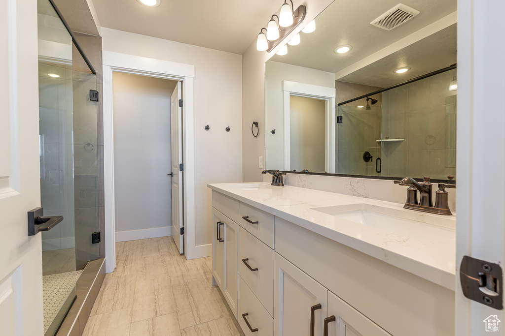 Full bathroom with a stall shower, double vanity, baseboards, and recessed lighting